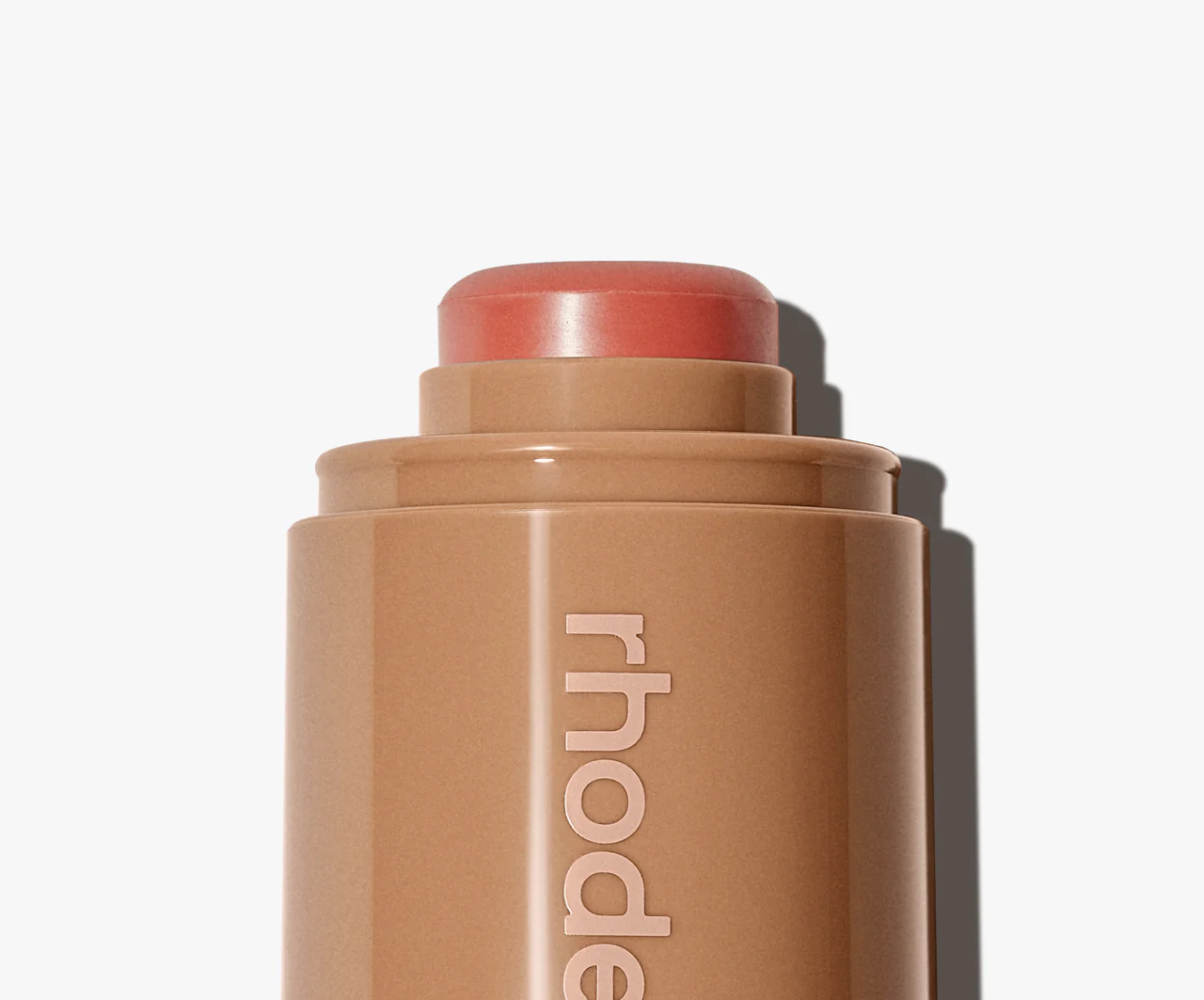 Cosmetic stick with 'rhode' branding on a white background