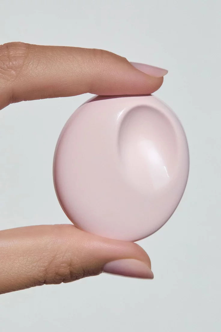 Hand holding the Glossier You Solid Perfume compact against a light gray background
