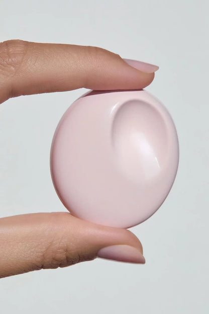 Hand holding the Glossier You Solid Perfume compact against a light gray background