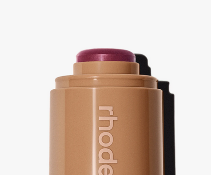 Cosmetic stick with purple top and 'rhode' branding on a white background