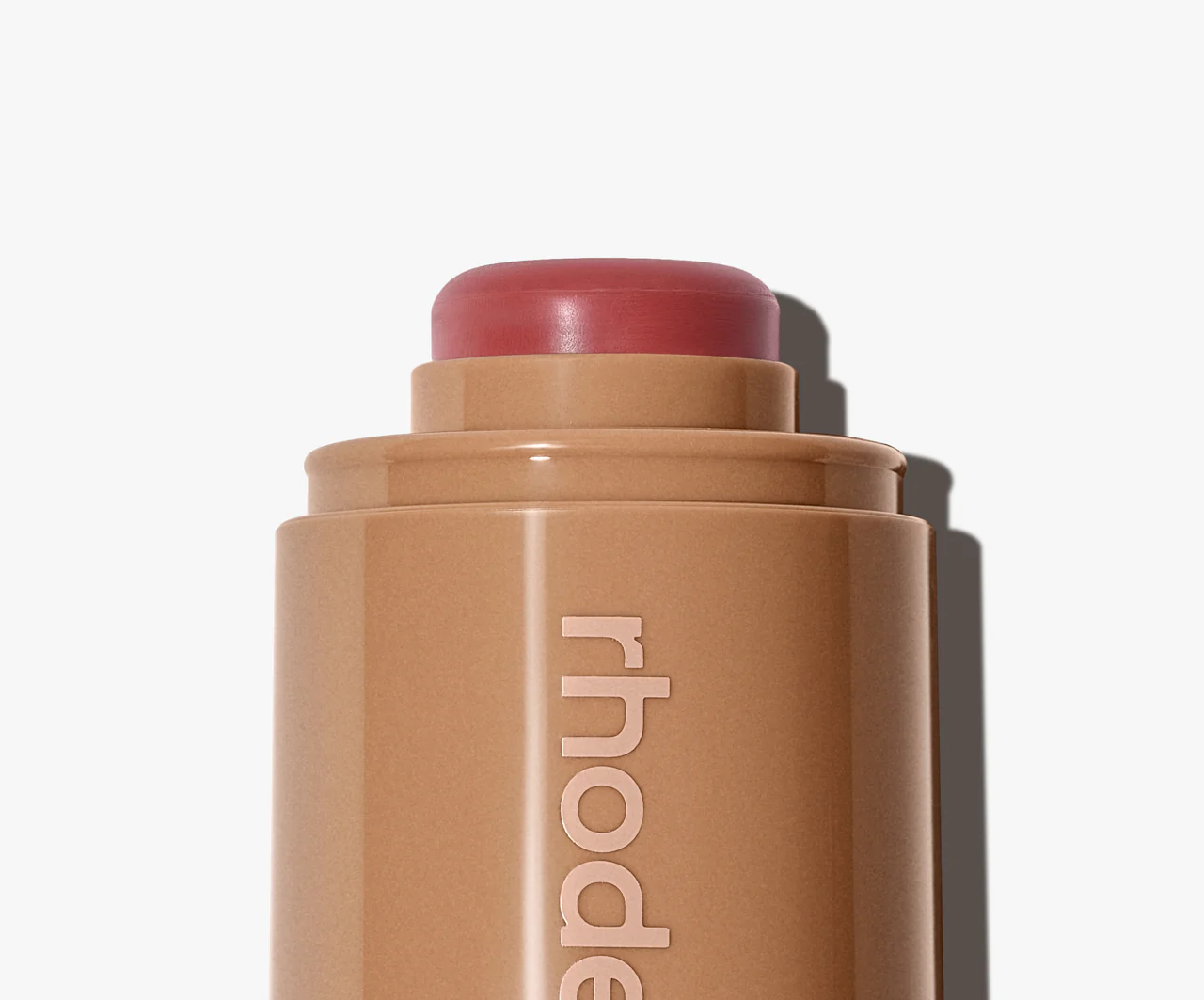 Cosmetic stick with 'rhode' branding on a white background