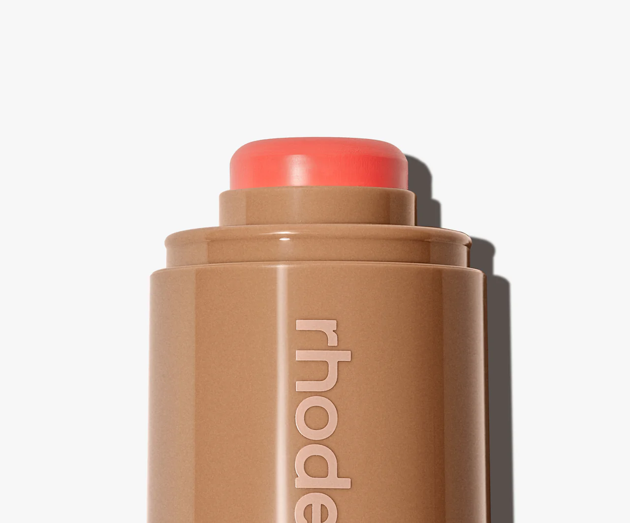 Makeup stick with coral-colored cap on a white background