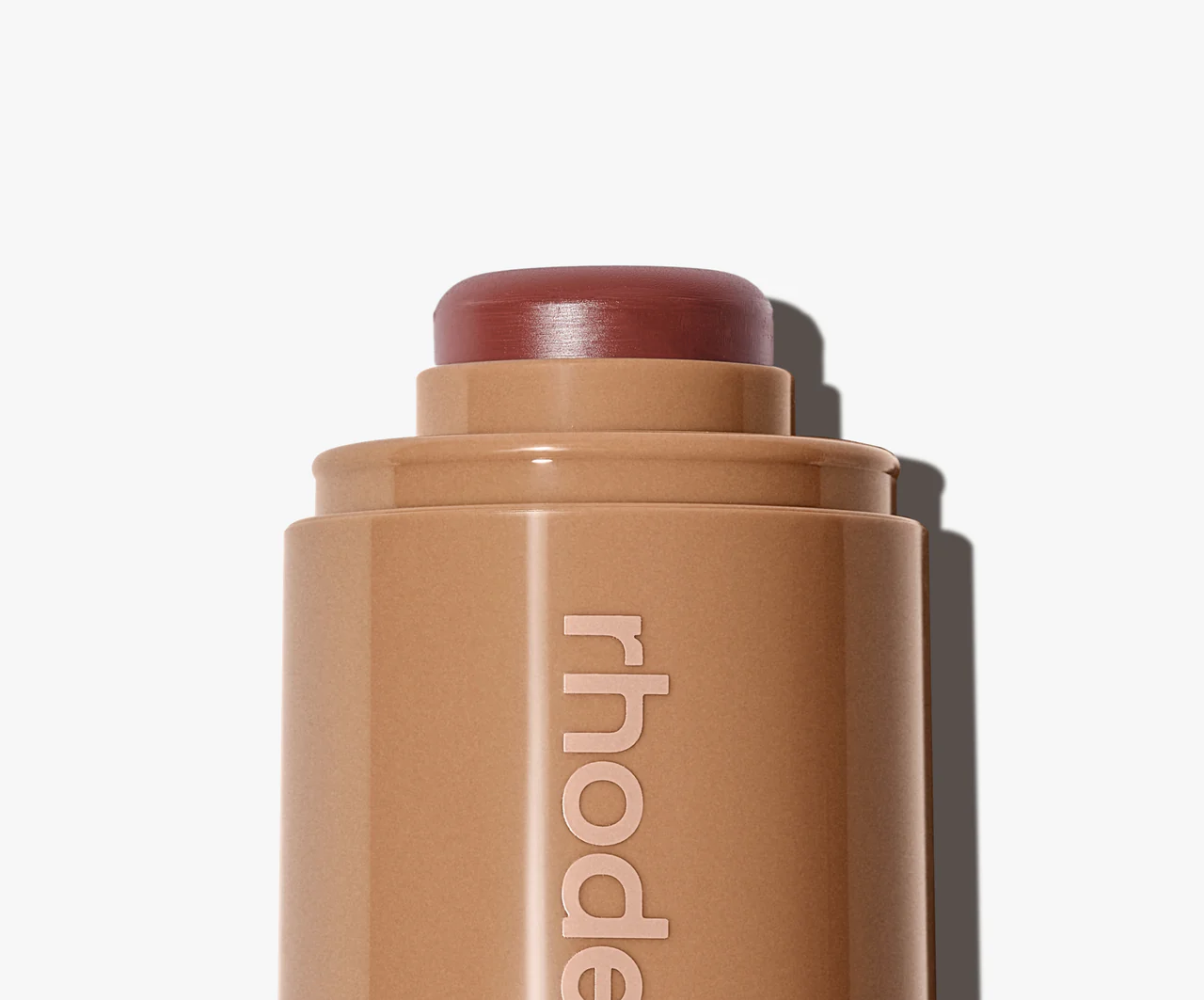 Cosmetic stick with 'rhode' branding on a white background
