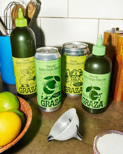 Graza olive oil bottles and cans on a kitchen counter with limes, a lemon, and a funnel