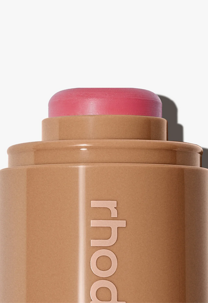Cosmetic stick with pink cap and 'rhode' branding on a white background